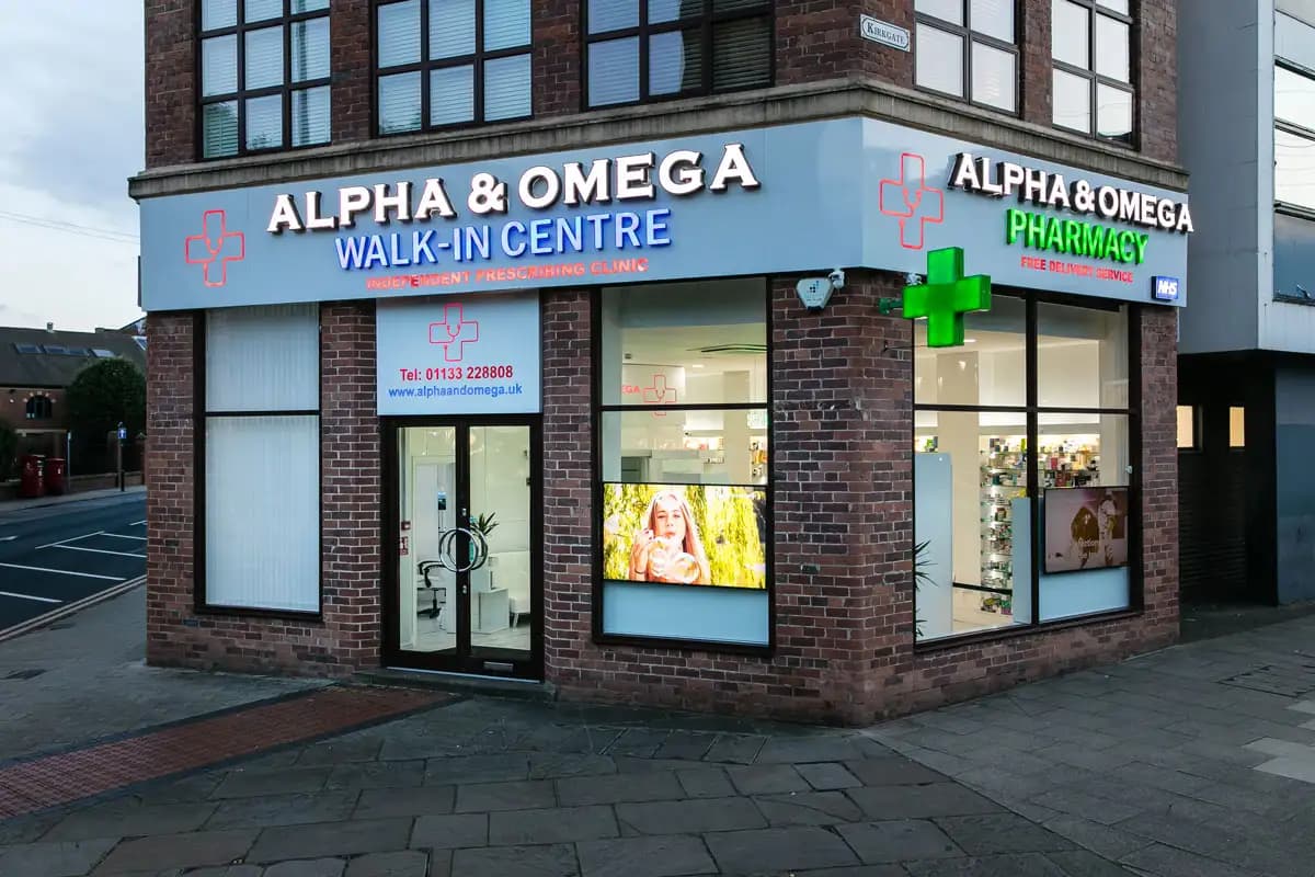 Alpha & Omega walk-in centre and pharmacy shopfront on a street corner