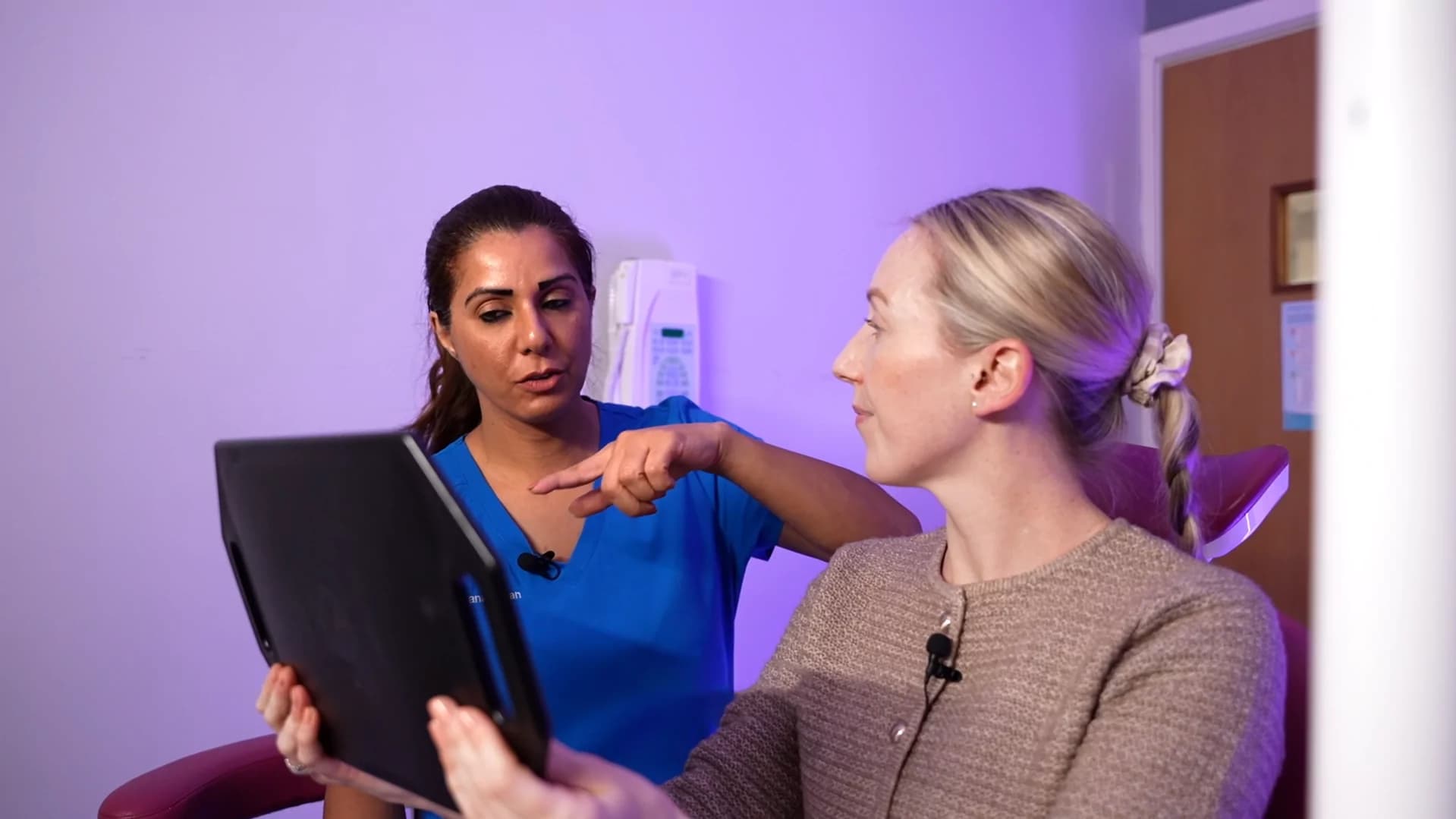 Clinician showing a patient a tablet during a consultation at Dr Farzana's clinic