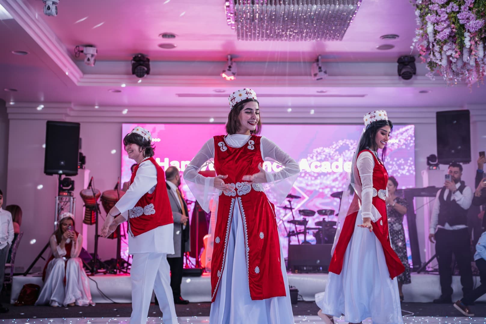 Performers in red and white costumes on stage at a Rose Event Yalda Night